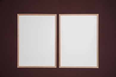 Photo of Empty frames on brown wall. Mockup for design