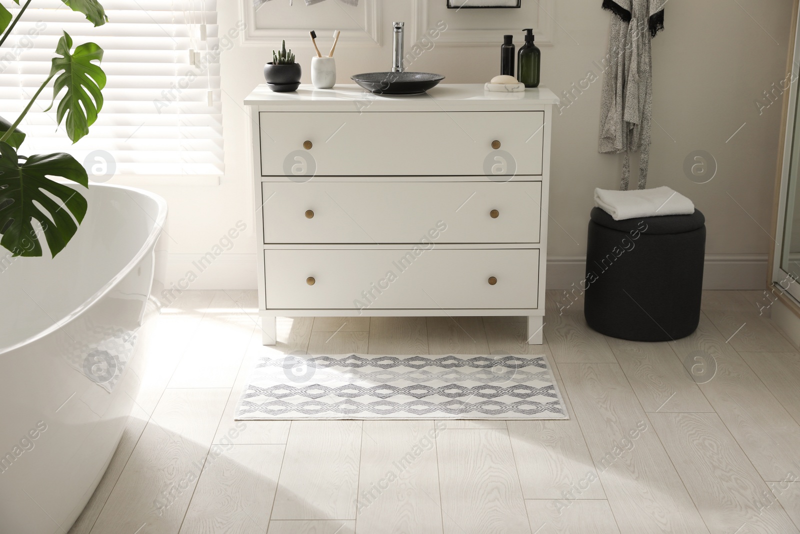 Photo of Stylish mat with pattern near chest of drawers in bathroom