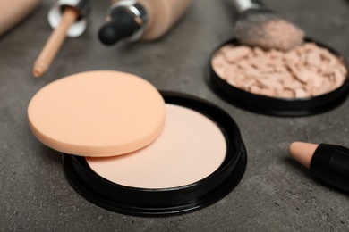 Photo of Composition with powder, skin foundation and beauty accessories on grey background