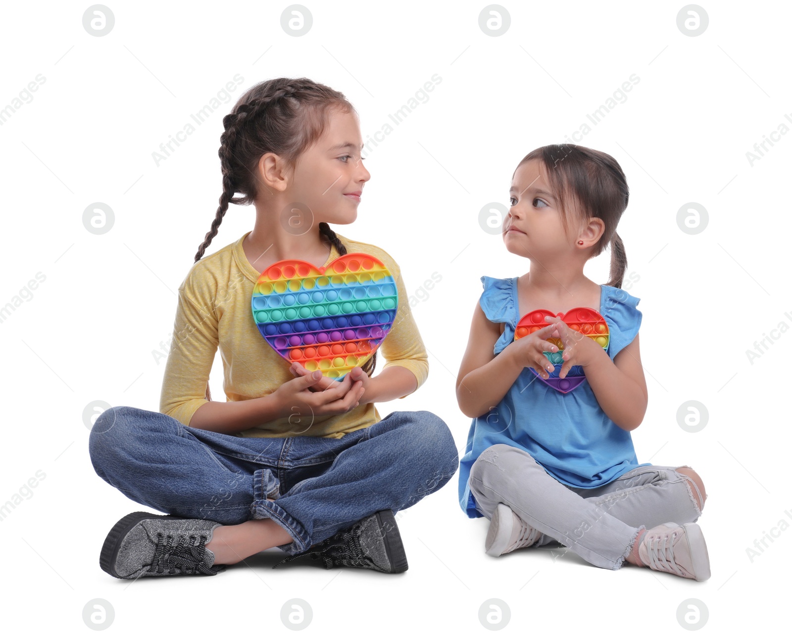 Photo of Little girls with pop it fidget toys on white background