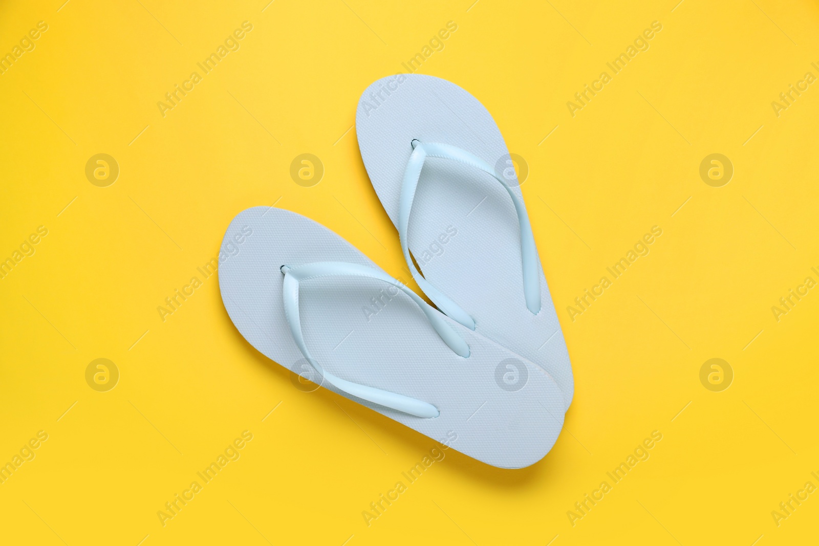 Photo of Stylish white flip flops on yellow background, top view