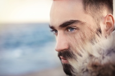 Photo of Portrait od bearded handsome man near sea, closeup view. Space for text