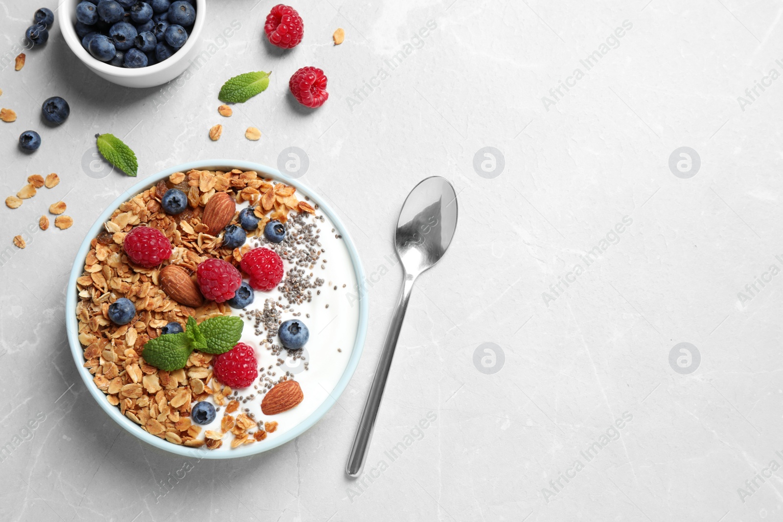 Photo of Healthy homemade granola with yogurt and berries served on light grey table, flat lay. Space for text