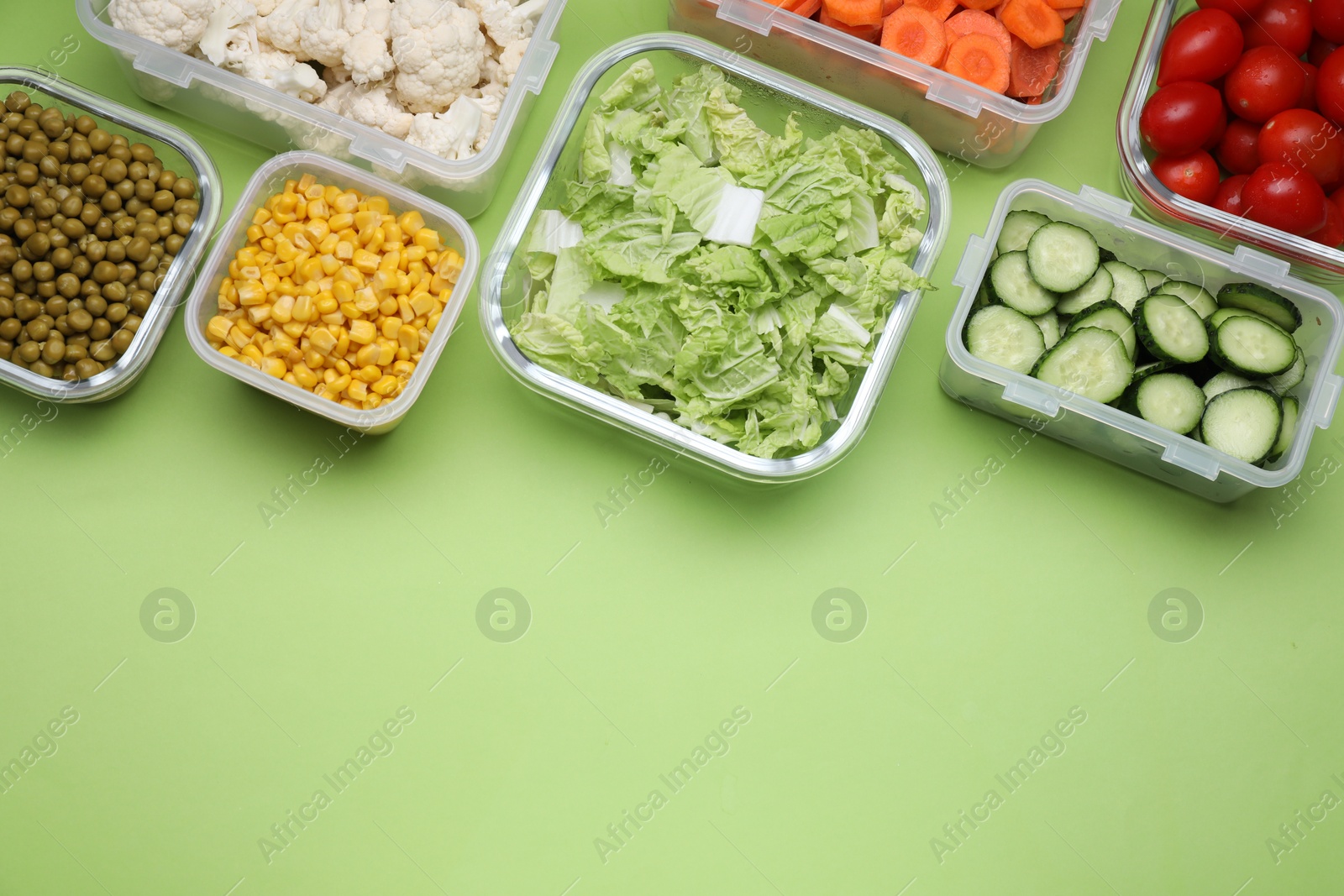 Photo of Plastic and glass containers with different fresh products on light green background, flat lay. Space for text