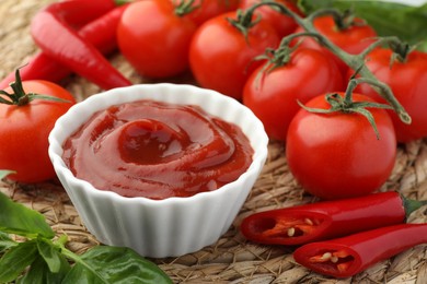 Bowl of tasty ketchup and ingredients on wicker mat, closeup