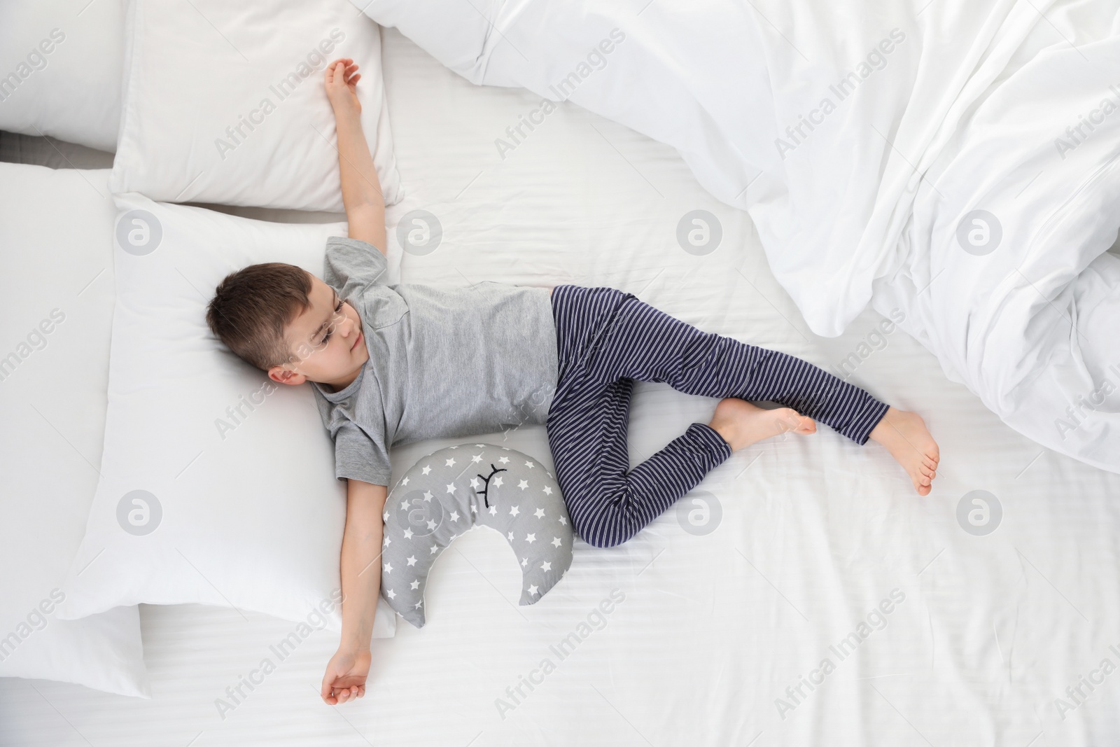 Photo of Cute little boy with toy sleeping on bed, above view