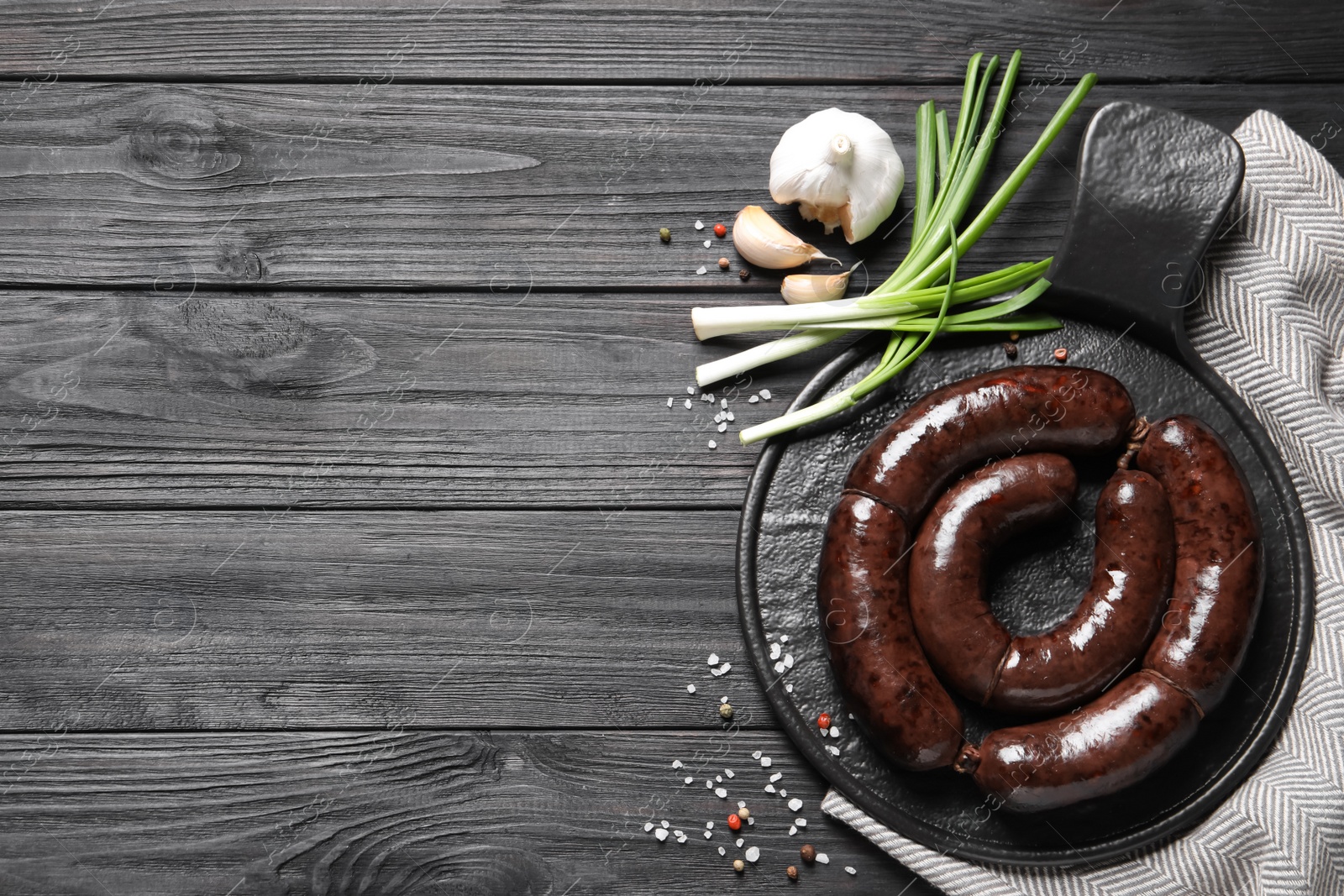 Photo of Tasty blood sausages served on black wooden table, flat lay. Space for text
