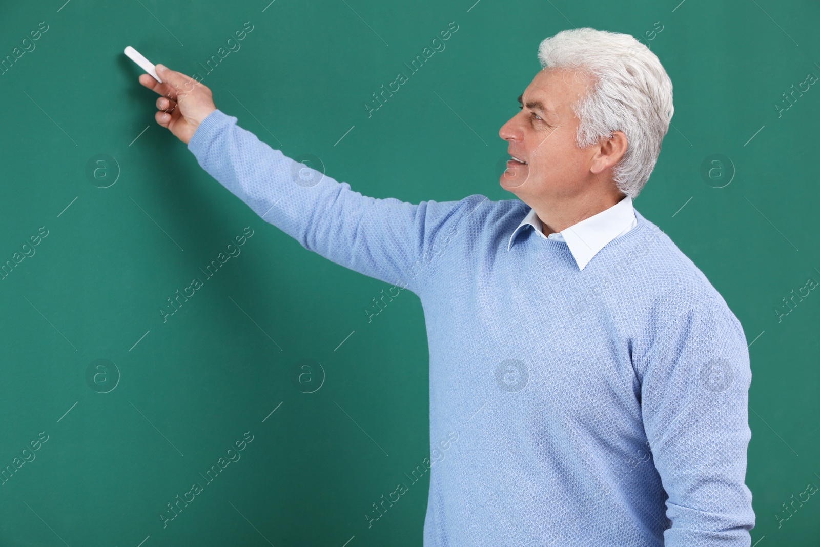 Photo of Portrait of senior teacher with chalk at green board