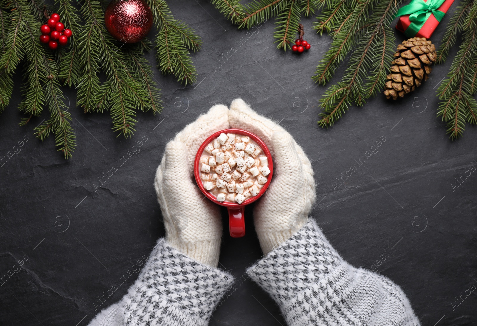 Photo of Woman with cup of delicious hot cocoa at black table, top view