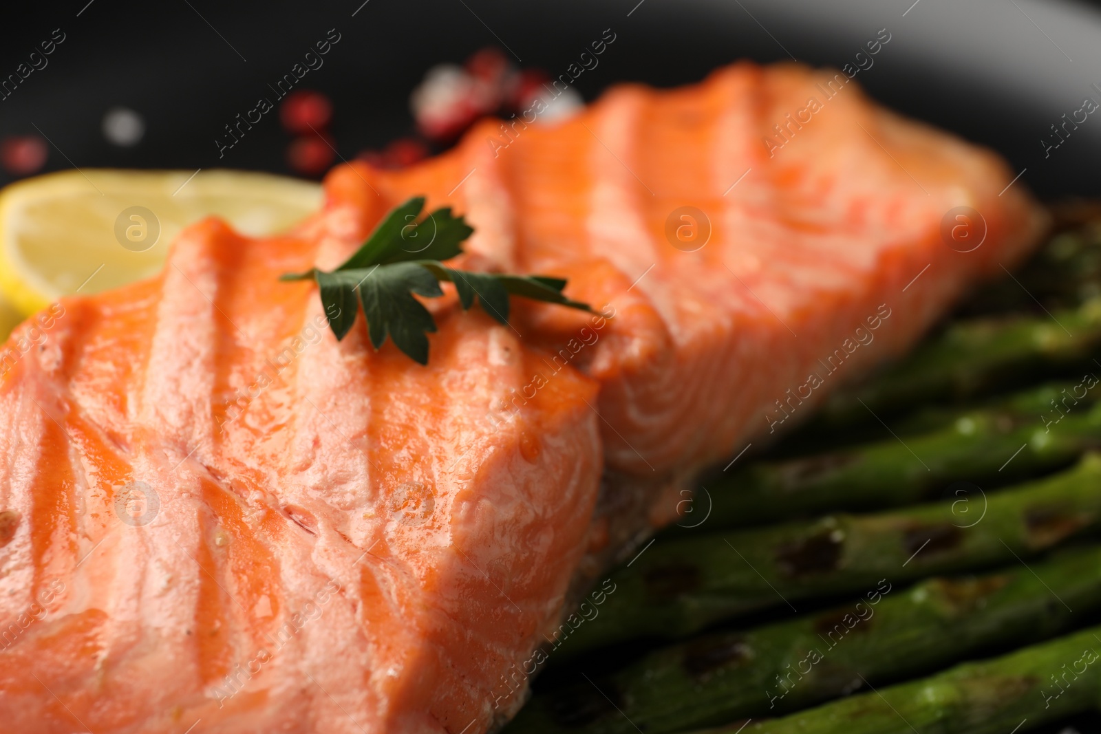 Photo of Tasty grilled salmon with asparagus and parsley on plate, closeup