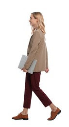 Young woman with laptop walking against white background
