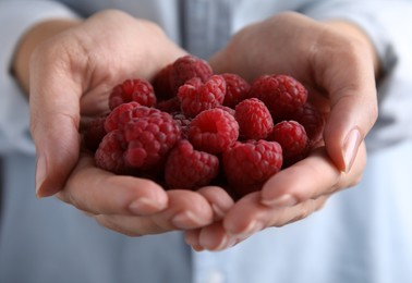 Photo of Woman holding red fresh ripe raspberries, closeup