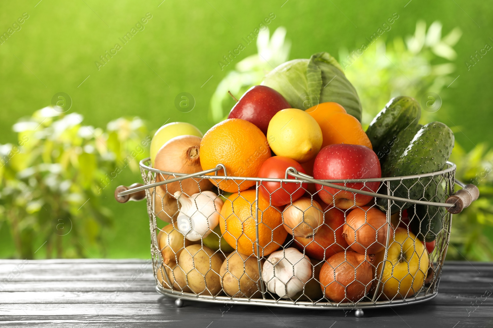 Photo of Basket full of fresh vegetables and fruits on table outdoors, space for text