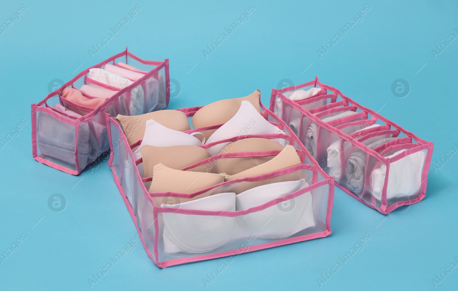 Photo of Transparent organizers with underwear on light blue background