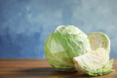 Photo of Whole and sliced cabbages on wooden table