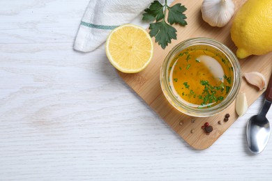 Photo of Jar of lemon sauce and ingredients on white wooden table, flat lay with space for text. Delicious salad dressing