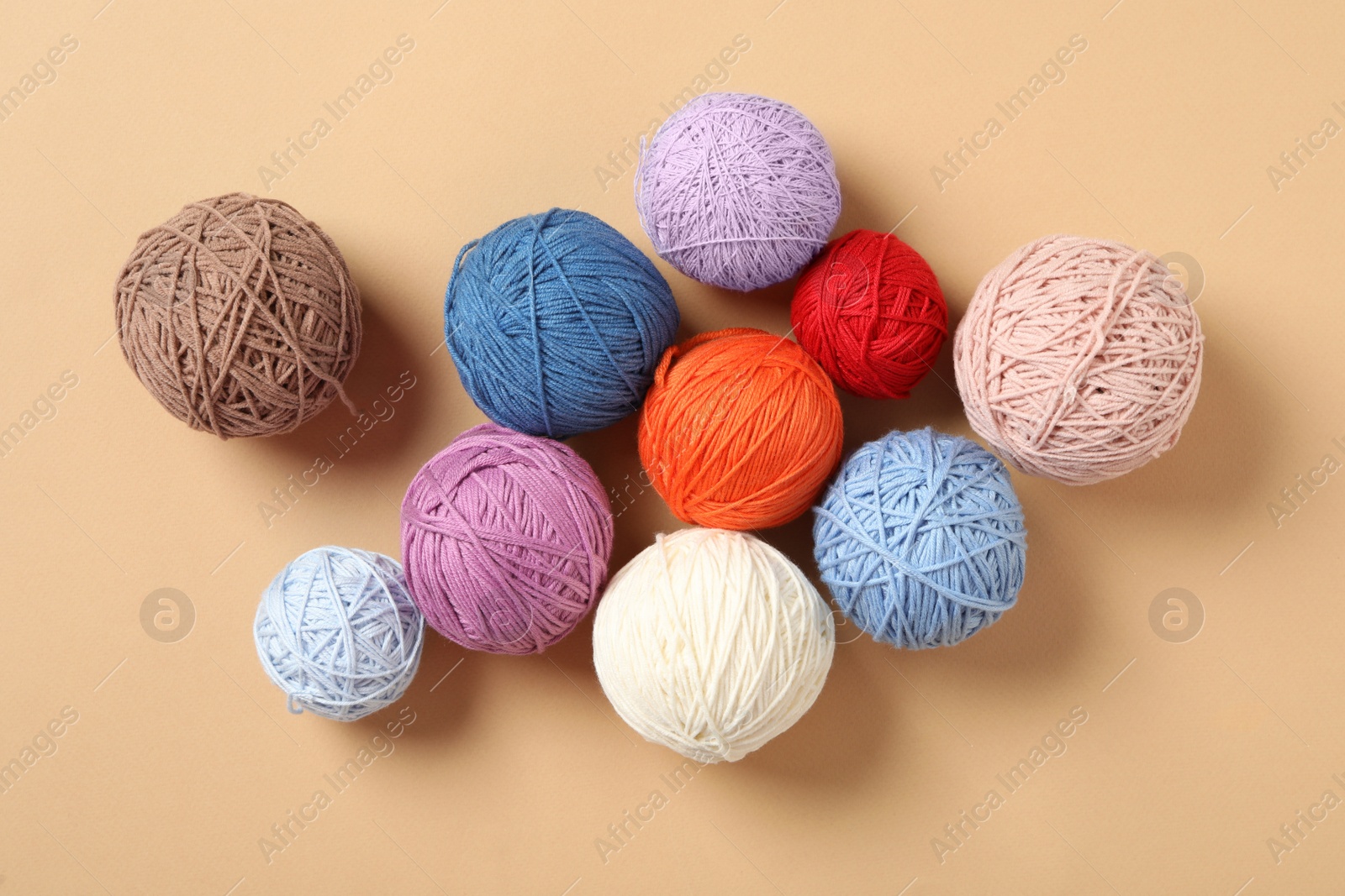 Photo of Colorful woolen yarns on beige background, flat lay