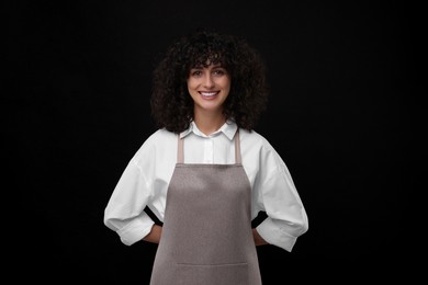 Happy woman wearing kitchen apron on black background. Mockup for design