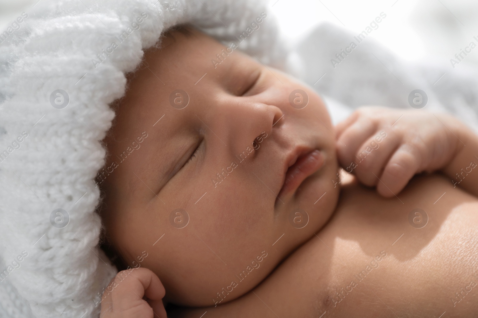 Photo of Closeup view of sleeping newborn baby in warm hat