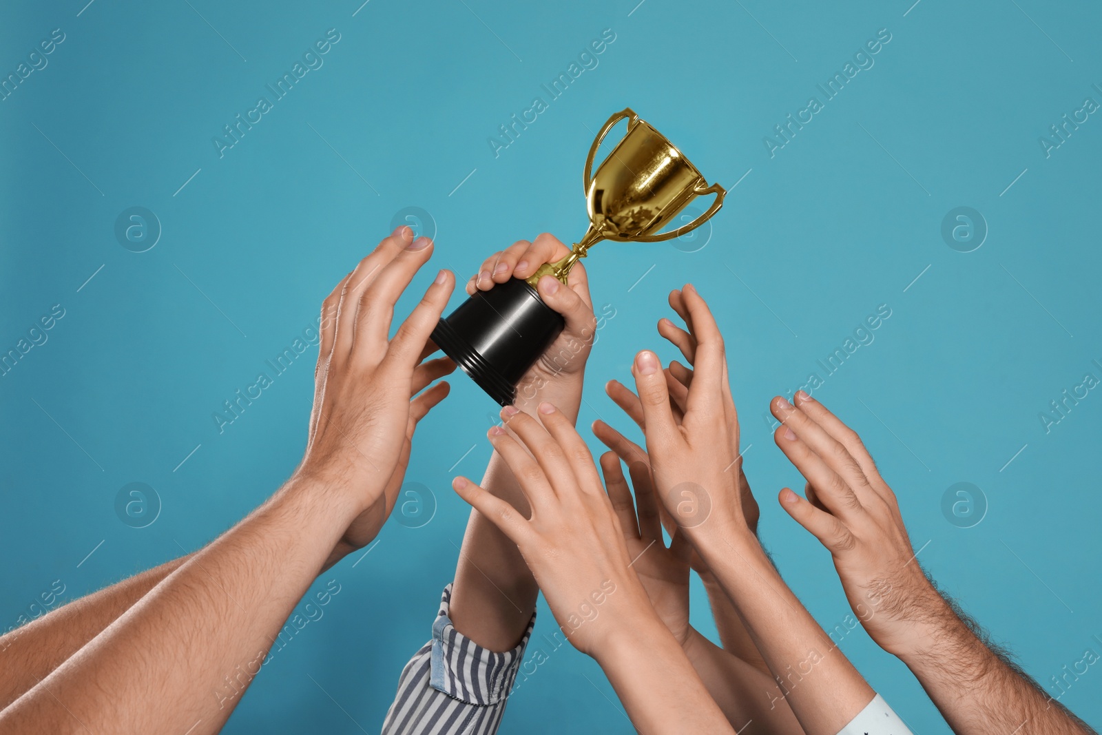 Photo of People with gold trophy cup on blue background, closeup