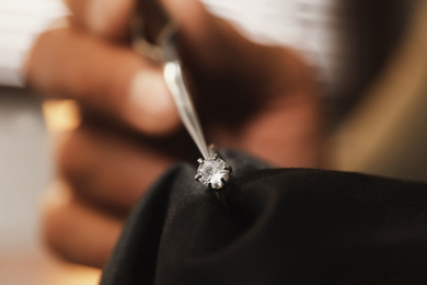Photo of Professional jeweler working with beautiful ring indoors, closeup