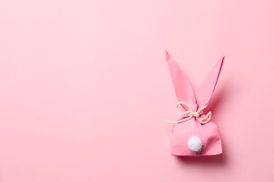 Photo of Creative Easter bunny gift bag on color background, top view with space for text