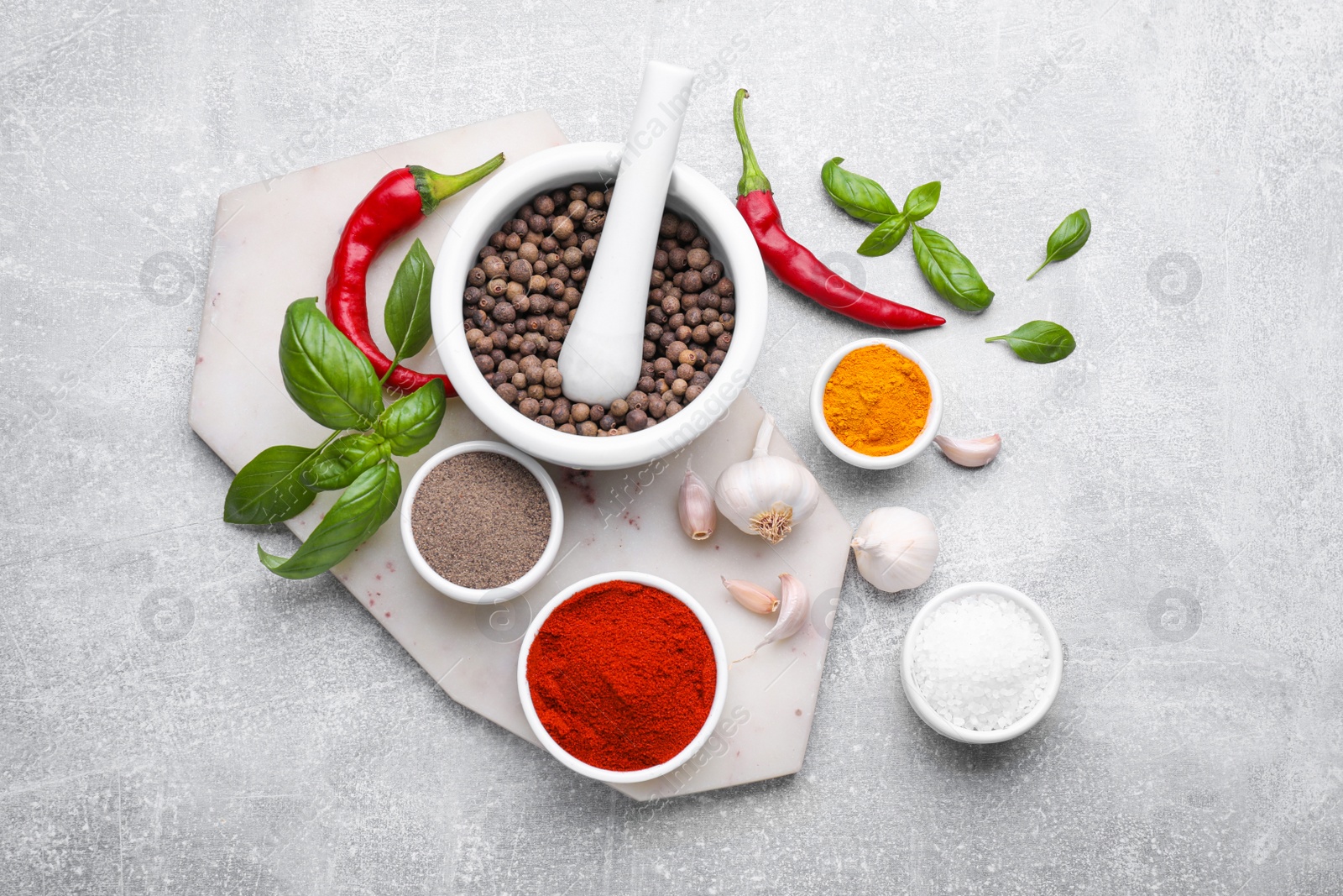 Photo of Mortar with pestle and different spices on light grey table, flat lay