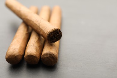 Photo of Many cigars on grey table, closeup. Space for text