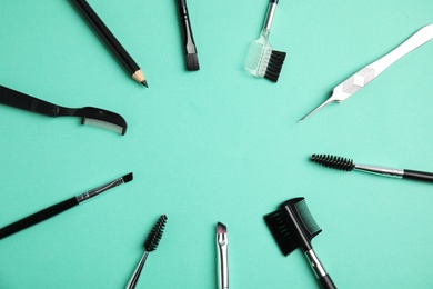 Set of professional eyebrow tools on turquoise background, flat lay. Space for text