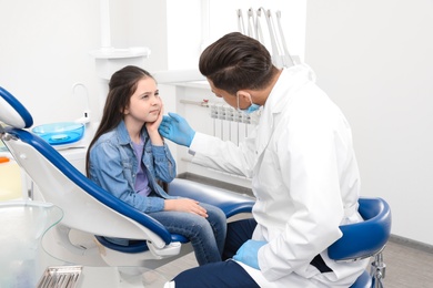 Photo of Professional dentist working with little girl in clinic