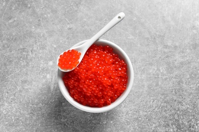 Ceramic bowl and spoon with delicious red caviar on table