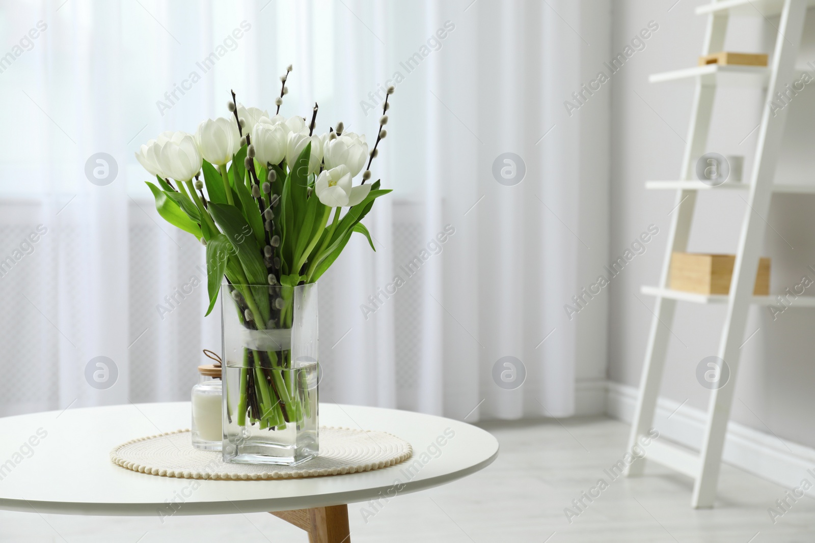 Photo of Beautiful bouquet of willow branches and tulips in vase on table indoors, space for text