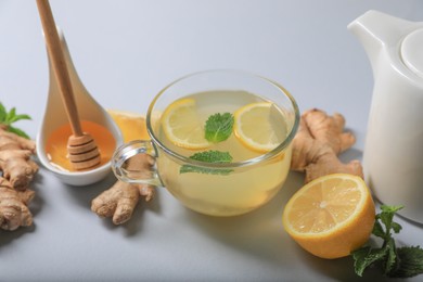 Photo of Delicious ginger tea and ingredients on light grey background