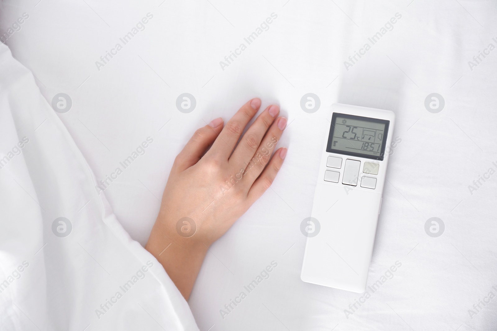 Photo of Woman with air conditioner remote control in bed, focus on hand