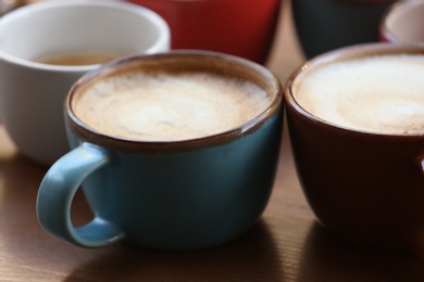 Cups of fresh aromatic coffee on wooden table, closeup