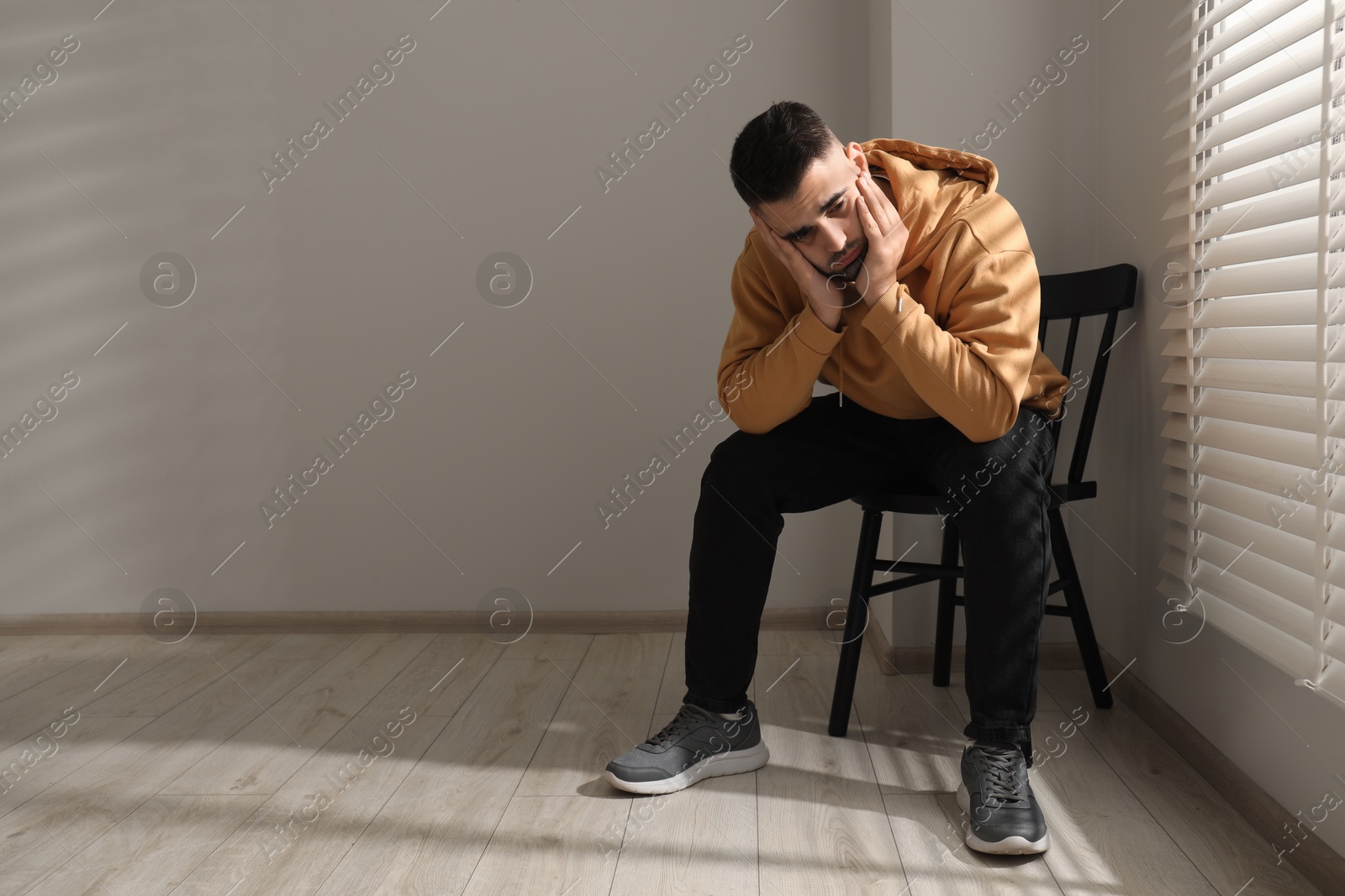 Photo of Sad man sitting on chair near window. Space for text