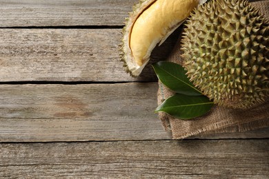 Photo of Fresh ripe durian fruits on wooden table, flat lay. Space for text