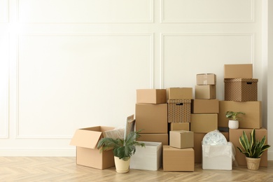 Photo of Cardboard boxes with stuff and houseplants in room, space for text. Moving day