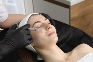 Photo of Cosmetologist giving lips injection to patient in clinic, closeup. Cosmetic surgery