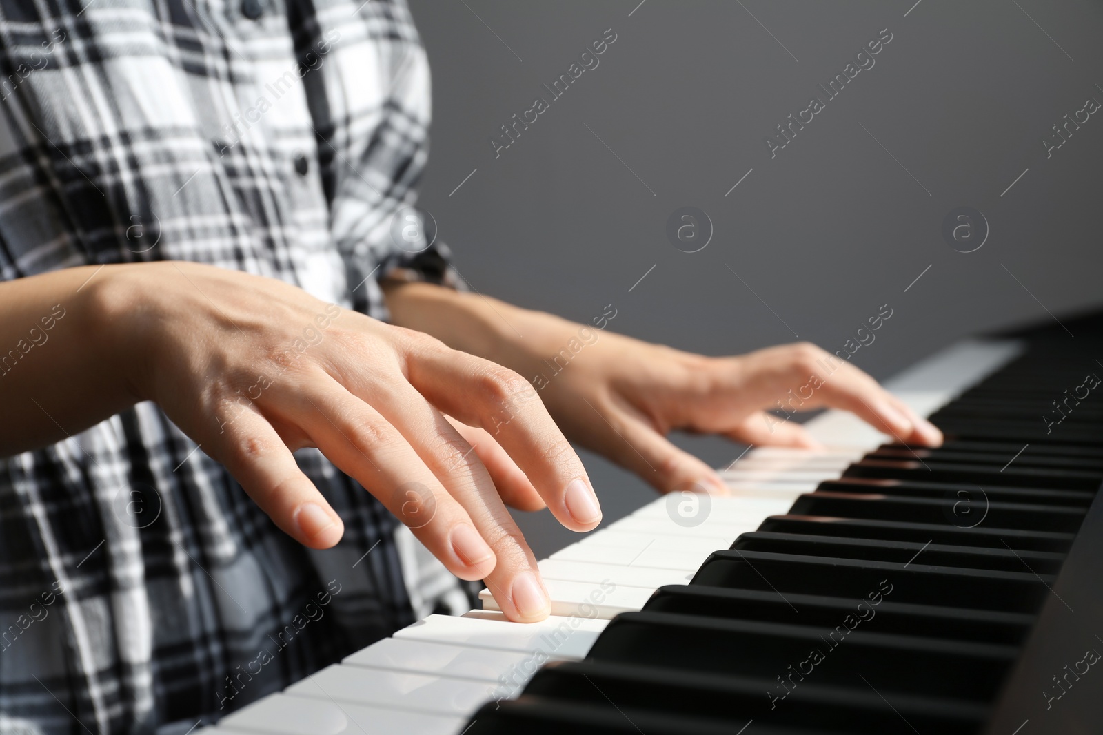 Photo of Young woman playing piano against grey background, closeup