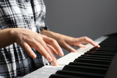 Photo of Young woman playing piano against grey background, closeup