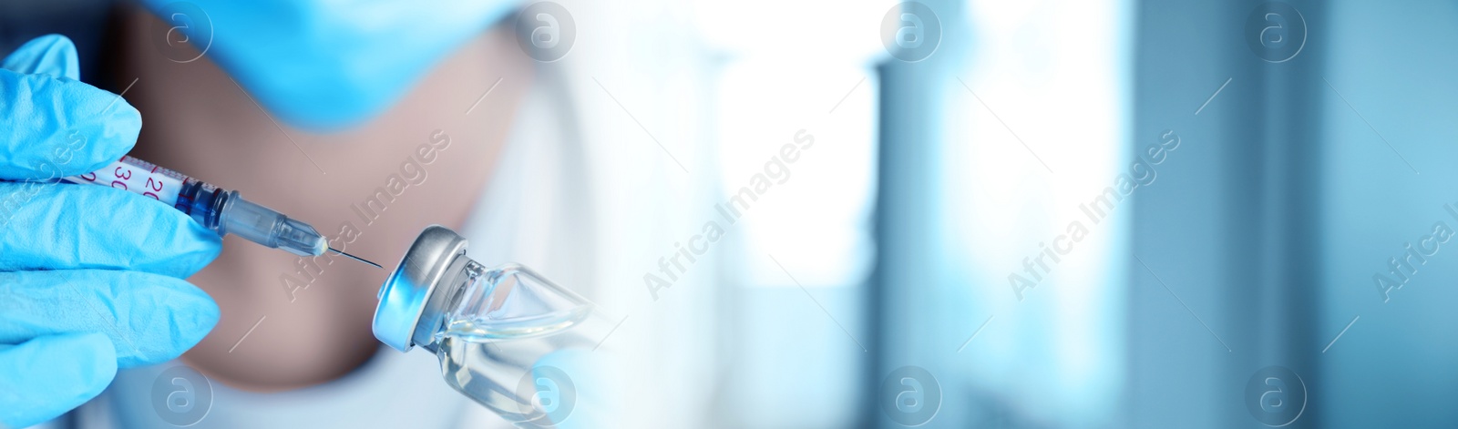 Image of Doctor filling syringe with medication from glass vial on blurred background, closeup. Banner design