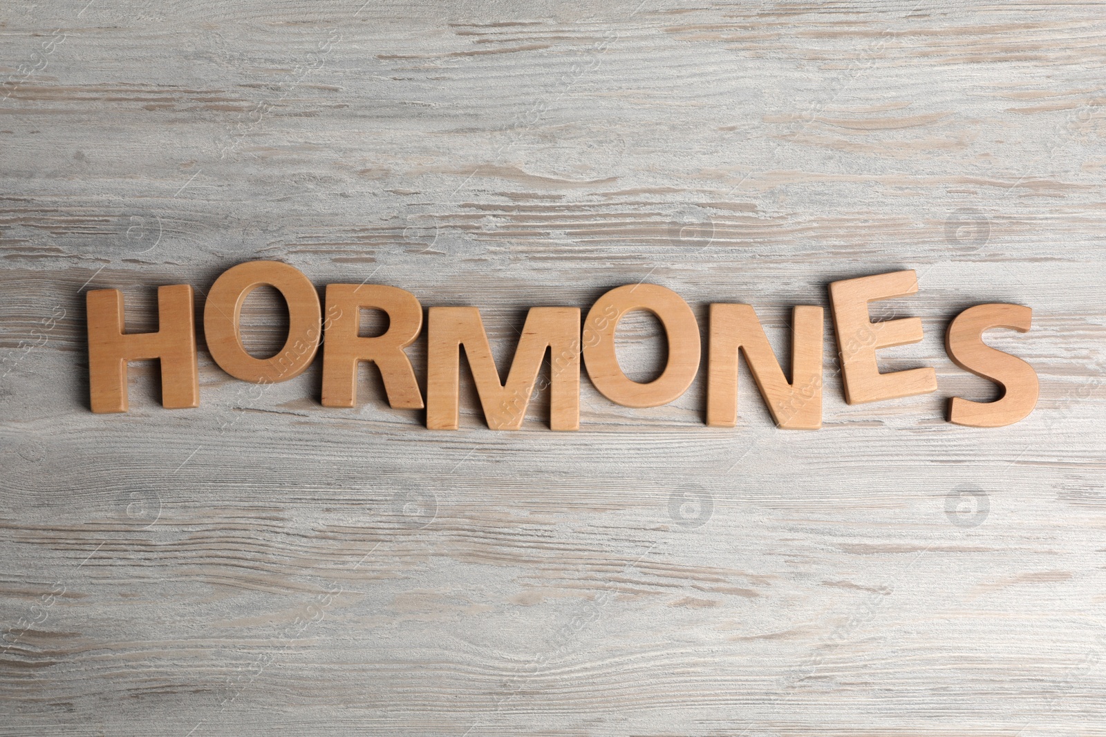 Photo of Word HORMONES made with wooden letters on table, flat lay