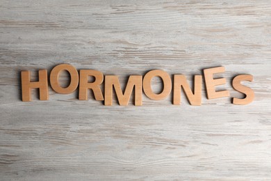 Word HORMONES made with wooden letters on table, flat lay