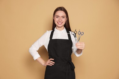 Photo of Portrait of happy hairdresser with professional scissors on beige background