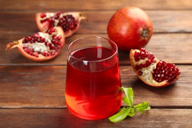 Photo of Tasty pomegranate juice in glass and fresh fruits on wooden table