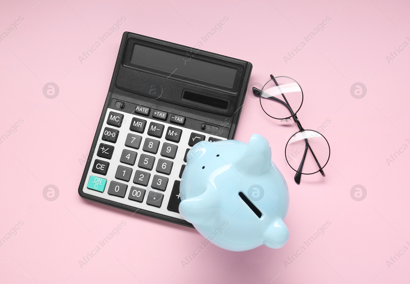 Photo of Calculator, glasses and piggy bank on pink background, flat lay