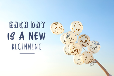 Inspirational text Each Day Is A New Beginning and woman holding balloons against blue sky