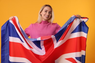Photo of Happy woman with flag of United Kingdom on orange background