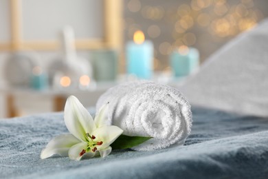 Photo of Spa composition with rolled towel and lily flower on massage table in wellness center